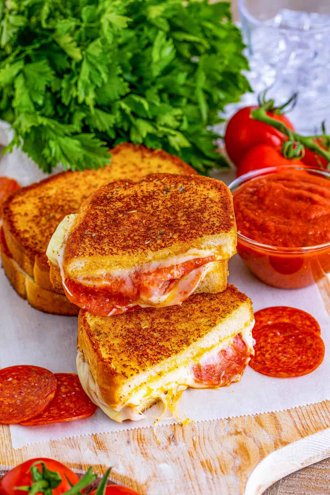 Stacked Pizza Grilled Cheese on white parchment paper on board.