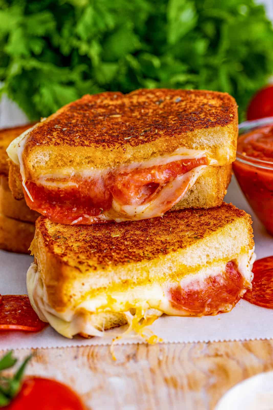 One Pizza Grilled Cheese cut in half stacked on top of one another showing melted inside.