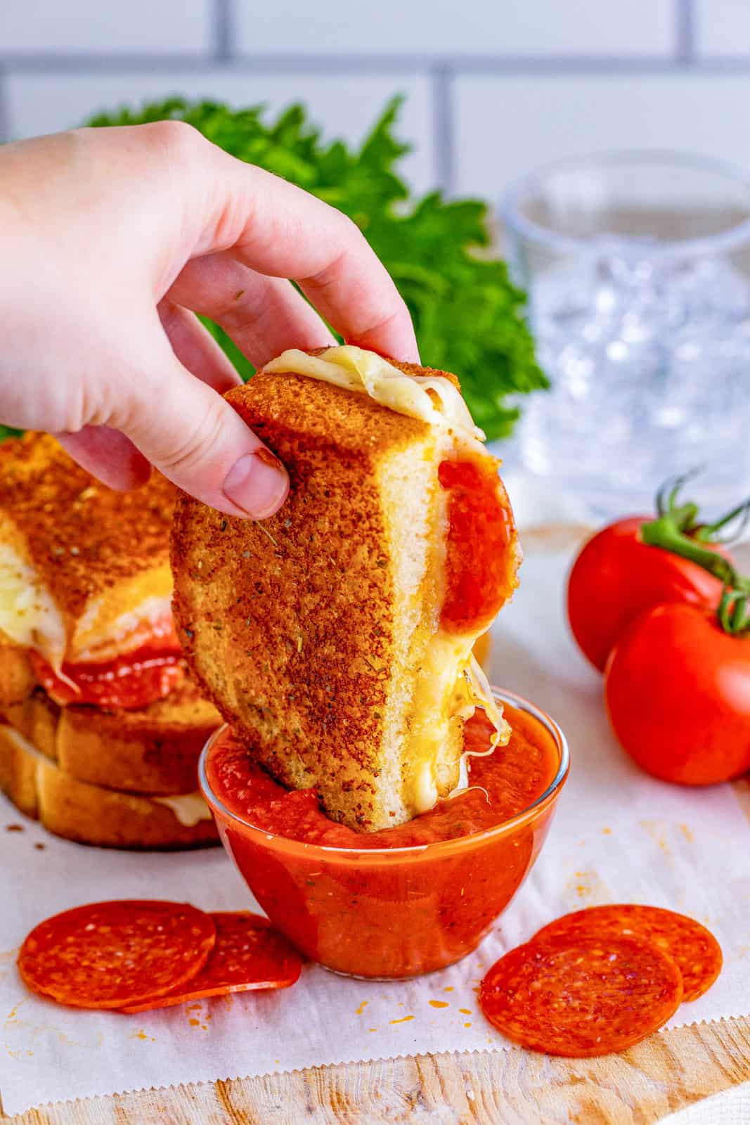 Hand dipping on half of grilled cheese into pizza sauce.