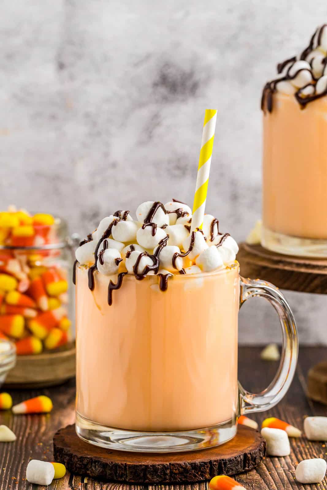 Candy Corn Hot Chocolate on coaster with garnishes and straw.