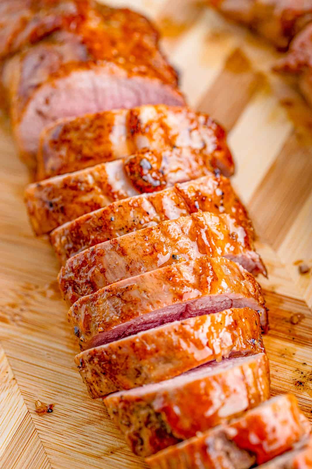 Overhead of glazed sliced Maple Dijon Pork Tenderloin on cutting board.