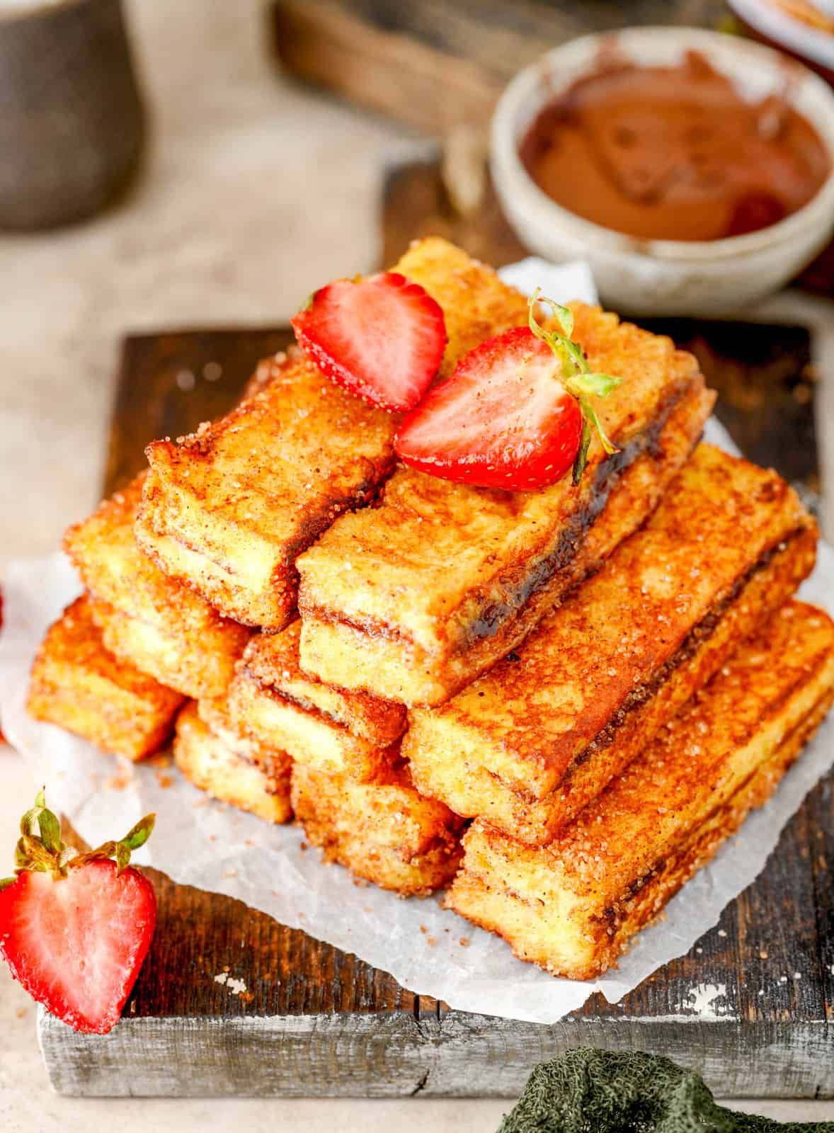 Stacked Nutella French Toast Sticks with strawberries on top.