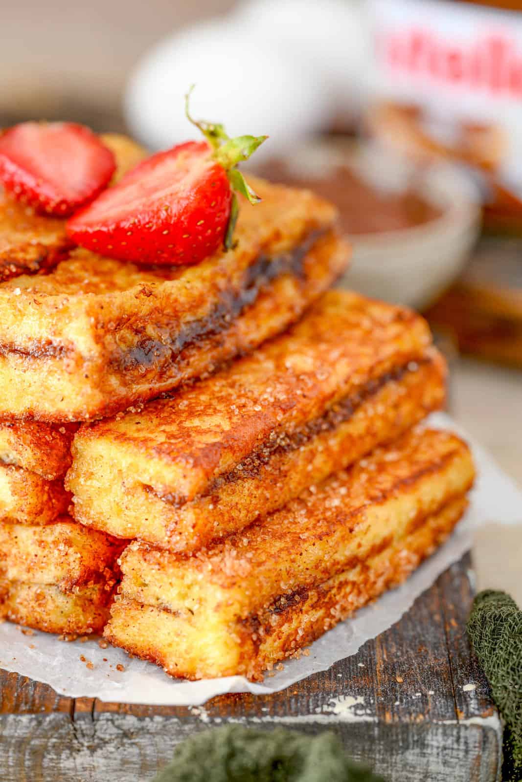 Side view of stacked Nutella French Toast Sticks on wooden platter.