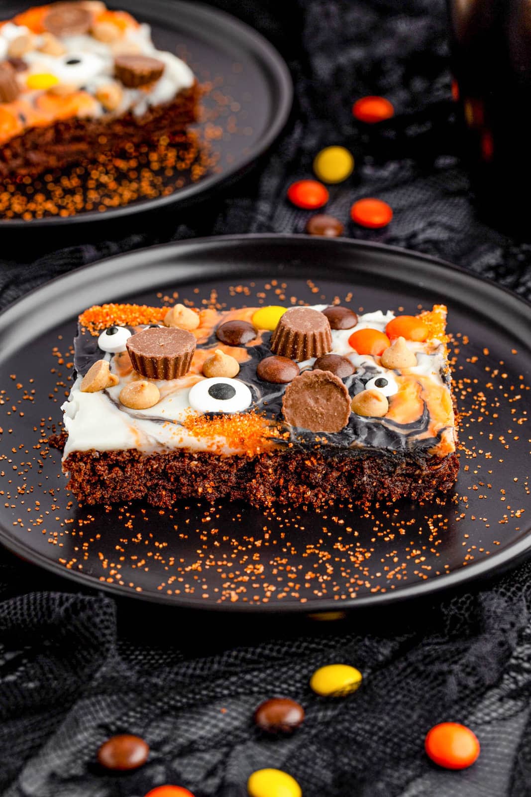 One of the cut Peanut Butter Halloween Brownies on black plate with orange sugar.