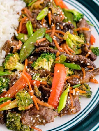 Square image of stir fry on plate next to rice.