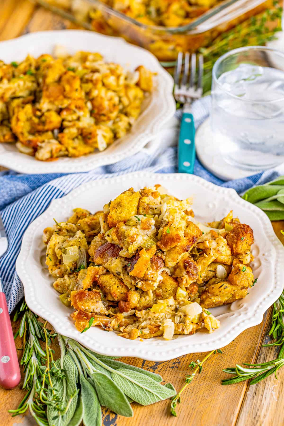Two plates of the Easy Stuffing Recipe with herbs, water and baking dish.