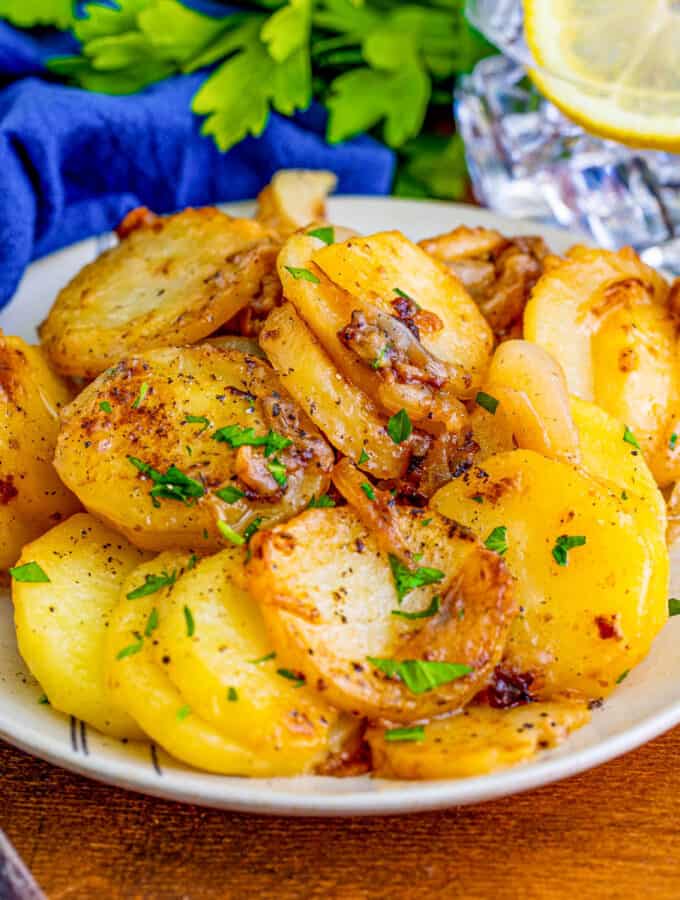 Close up square image of potatoes on white plate with parsley.