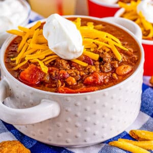 Square image close up of Chili in white bowl with toppings.