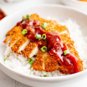 Close up of the Chicken Katsu recipe cut up on bowl over rice with sauce.