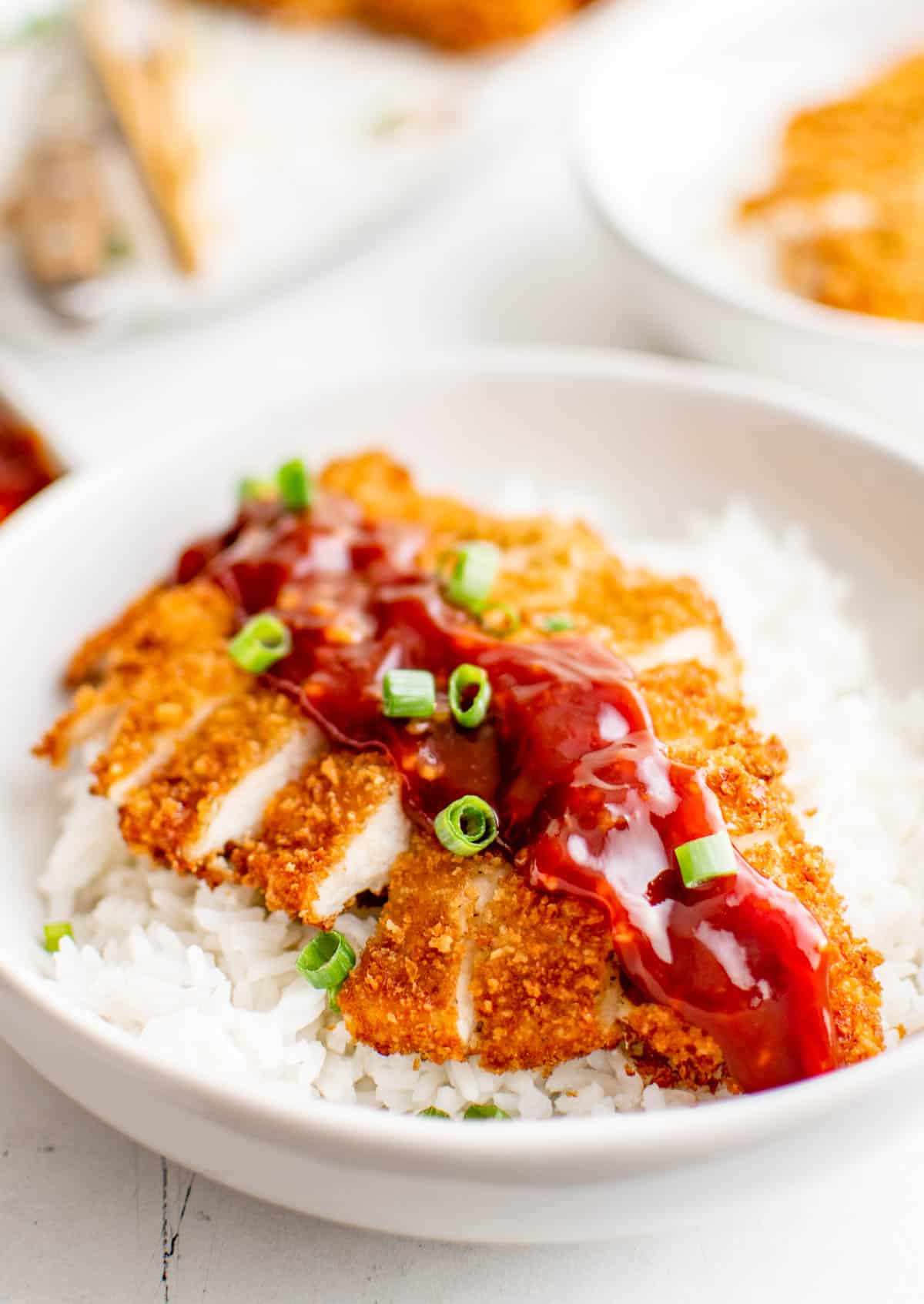 Cut up Chicken Katsu Recipe in bowl over rice with sauce.