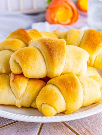 Square image of rolls stacked on top of one another on white plate.