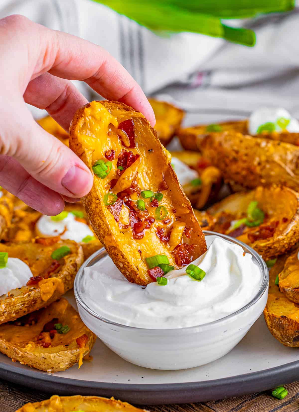 Hand dipping one of the Loaded Potato Skins in sour cream.