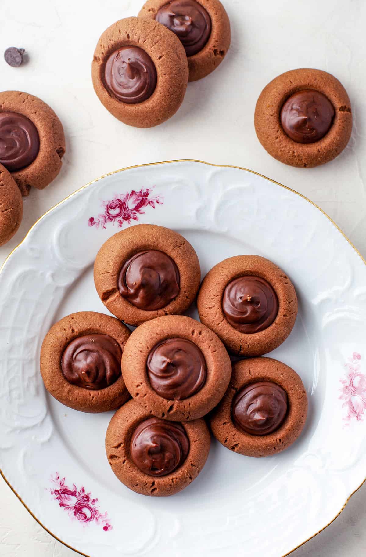 Overhead of Chocolate Thumbprint Cookies on plate with more cookies beside plate.