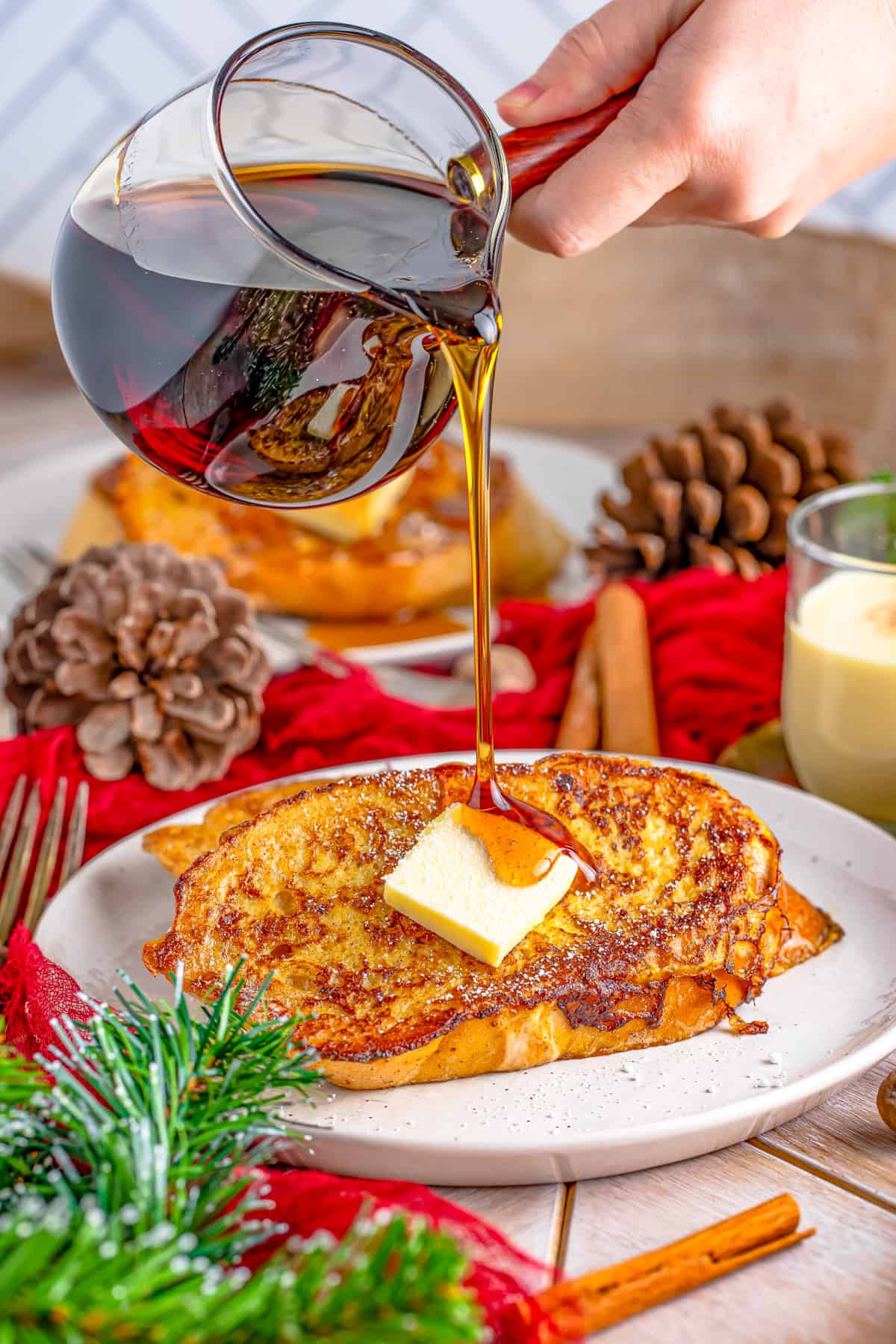 Styrup being poured over French Toast on plate with pat of butter.