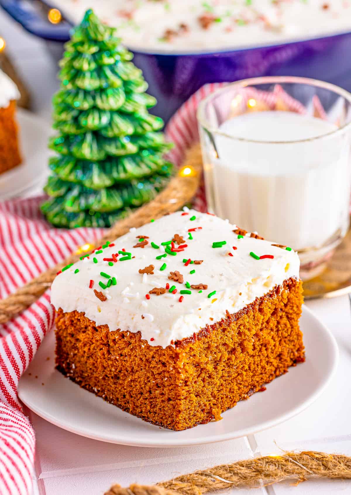 Slice of Gingerbread Cake on white plate with milk behind it.