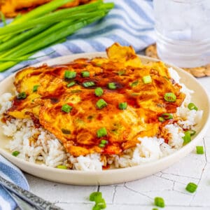 Close up square image of Egg Foo Young over rice.