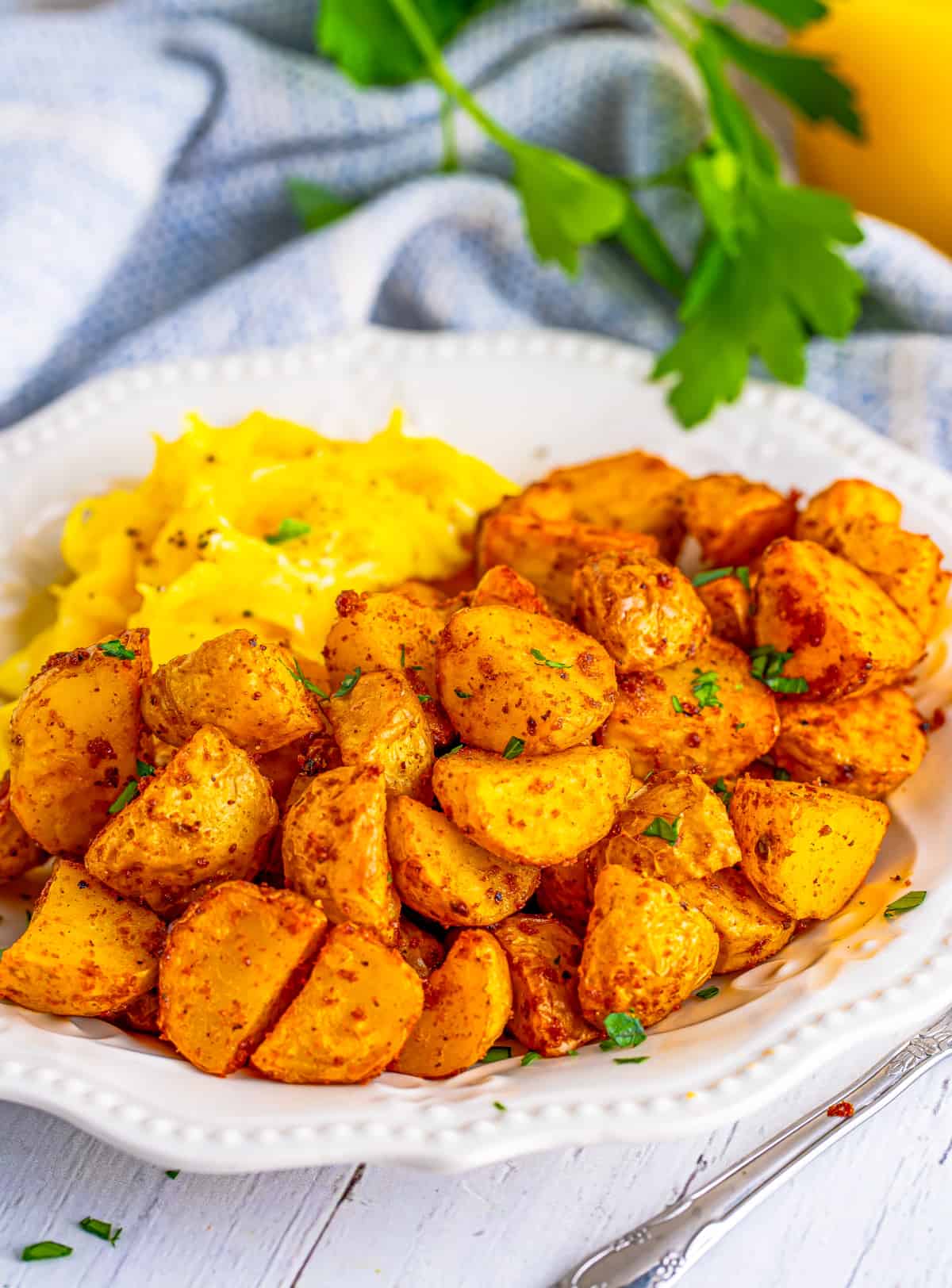 Air Fryer Breakfast Potatoes on white plate with scrambled eggs.
