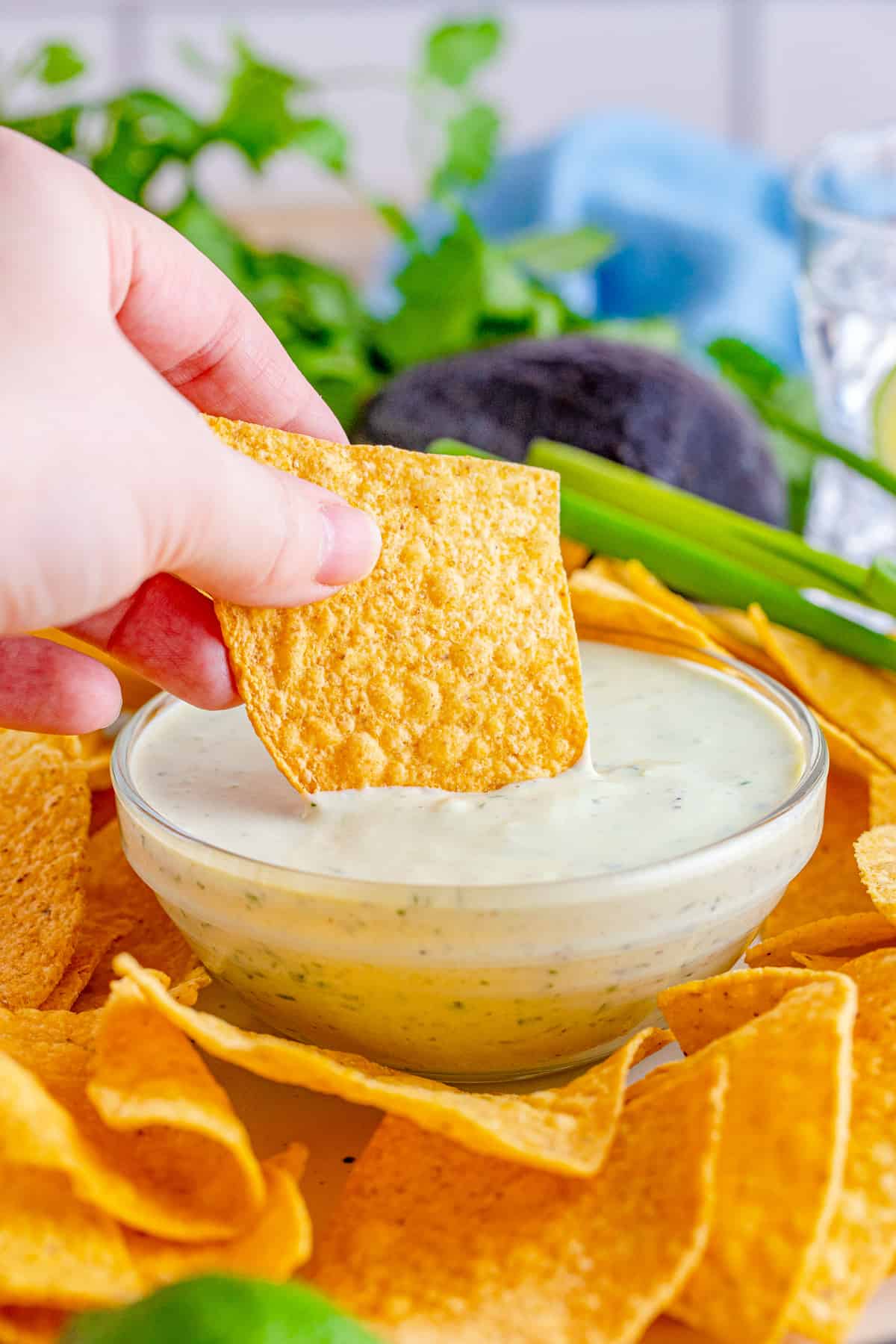 Hand dipping a chip into the Avocado Ranch.