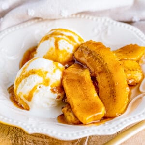 Close up square image of bananas in bowl with ice cream.