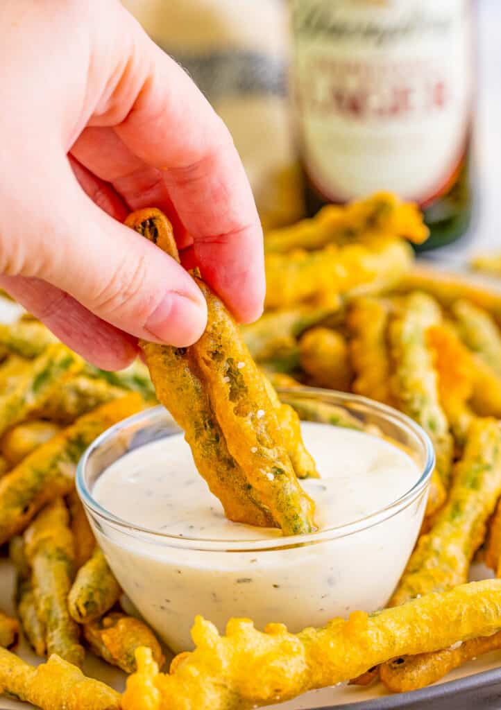 Hand dipping beans in ranch.