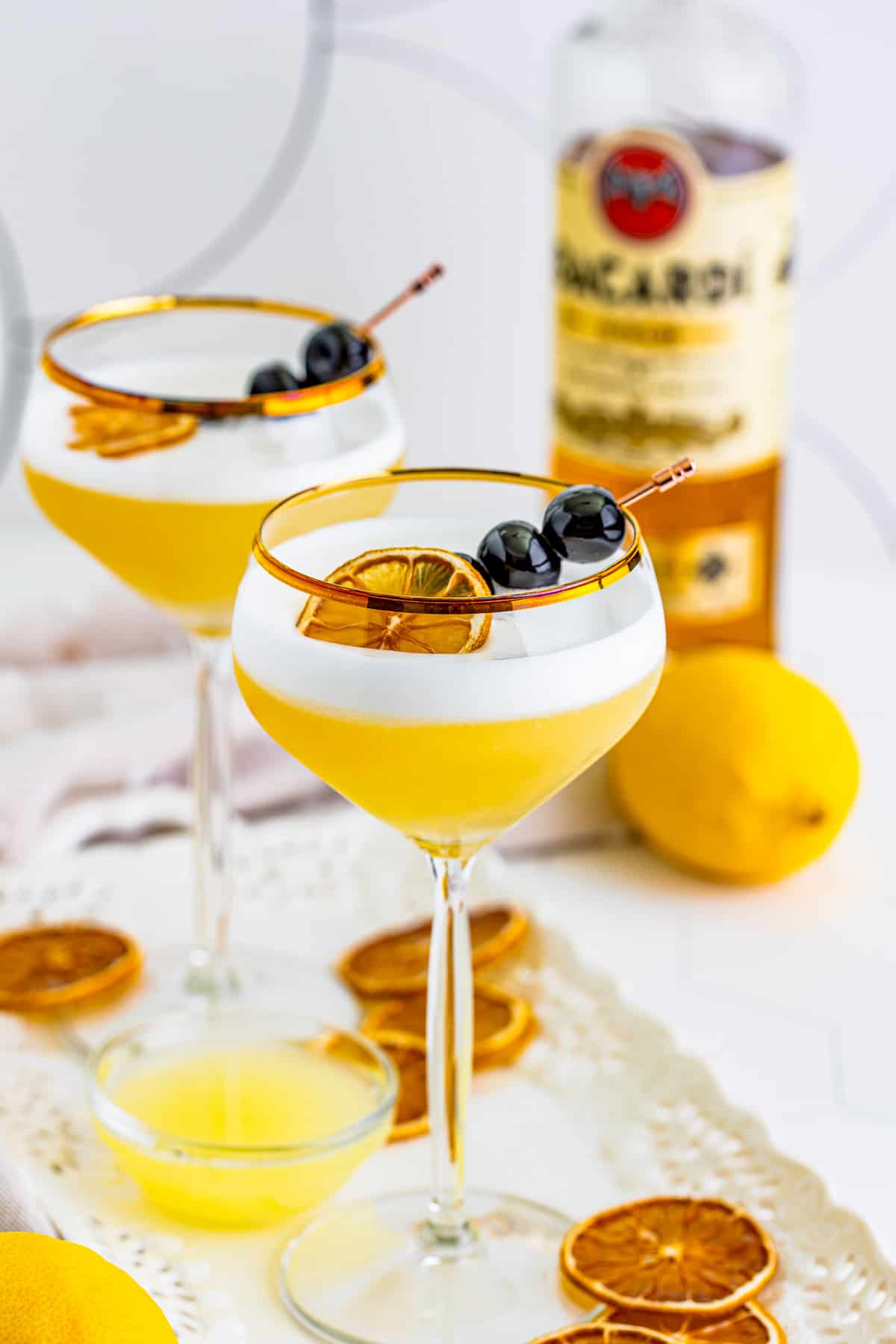 Rum Sour in two glasses with orange and cherry garnishes.