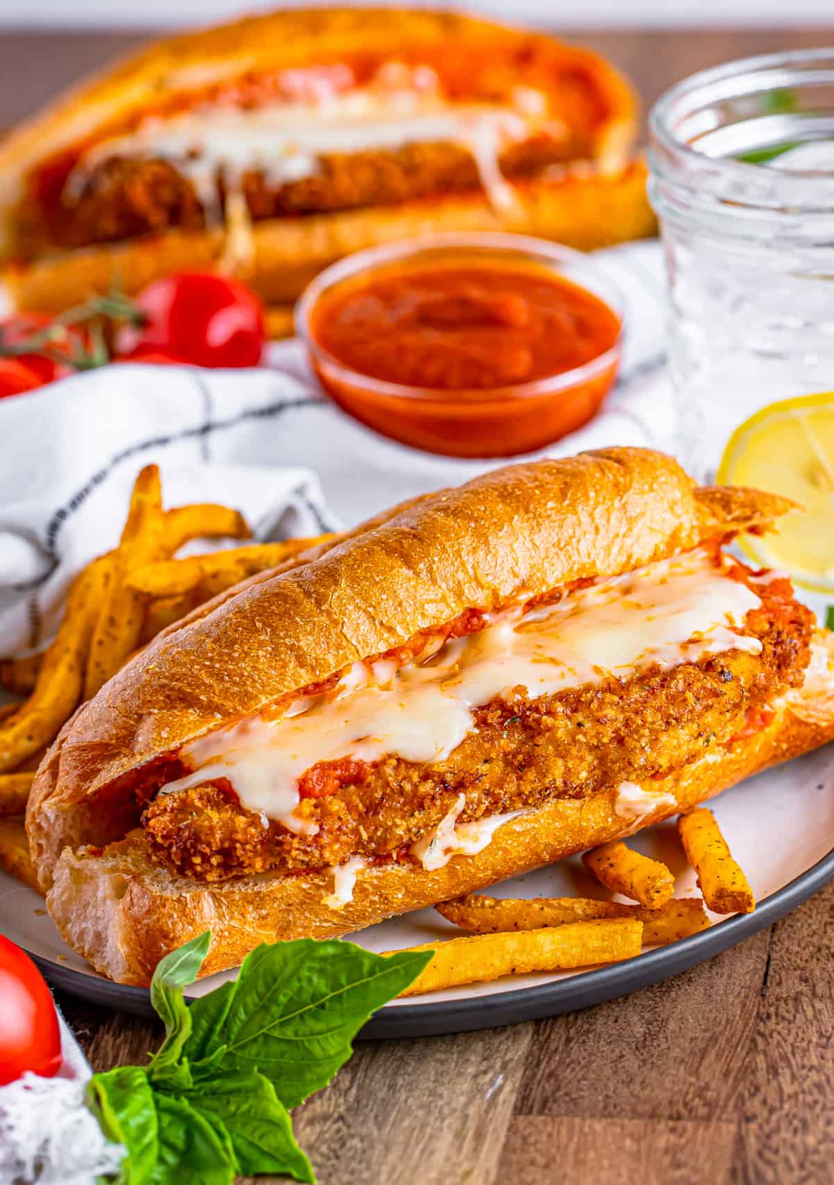 One of the Chicken Parmesan Sandwiches on plate with fries.