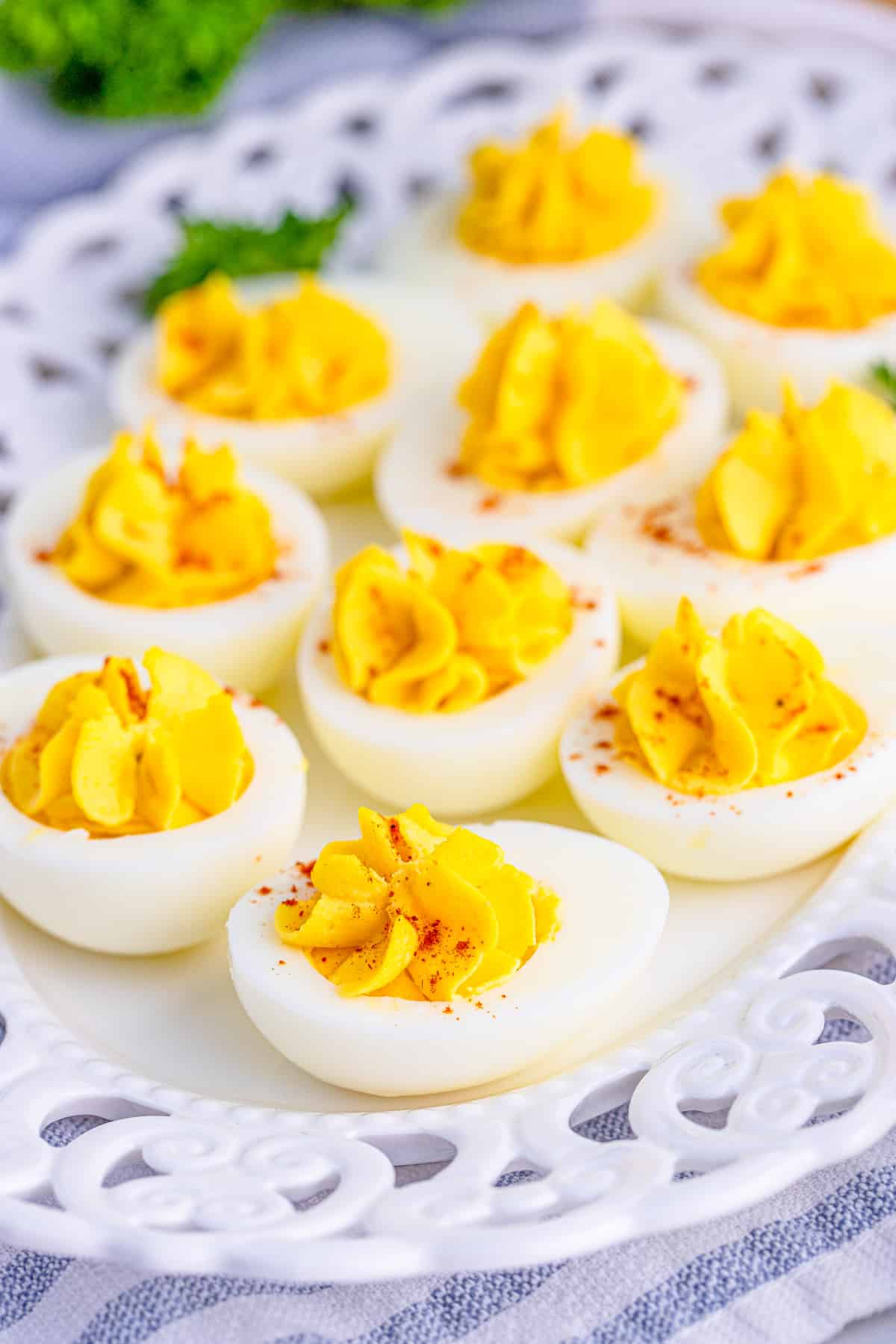 Finished Classic Deviled Eggs topped with paprika on white platter.