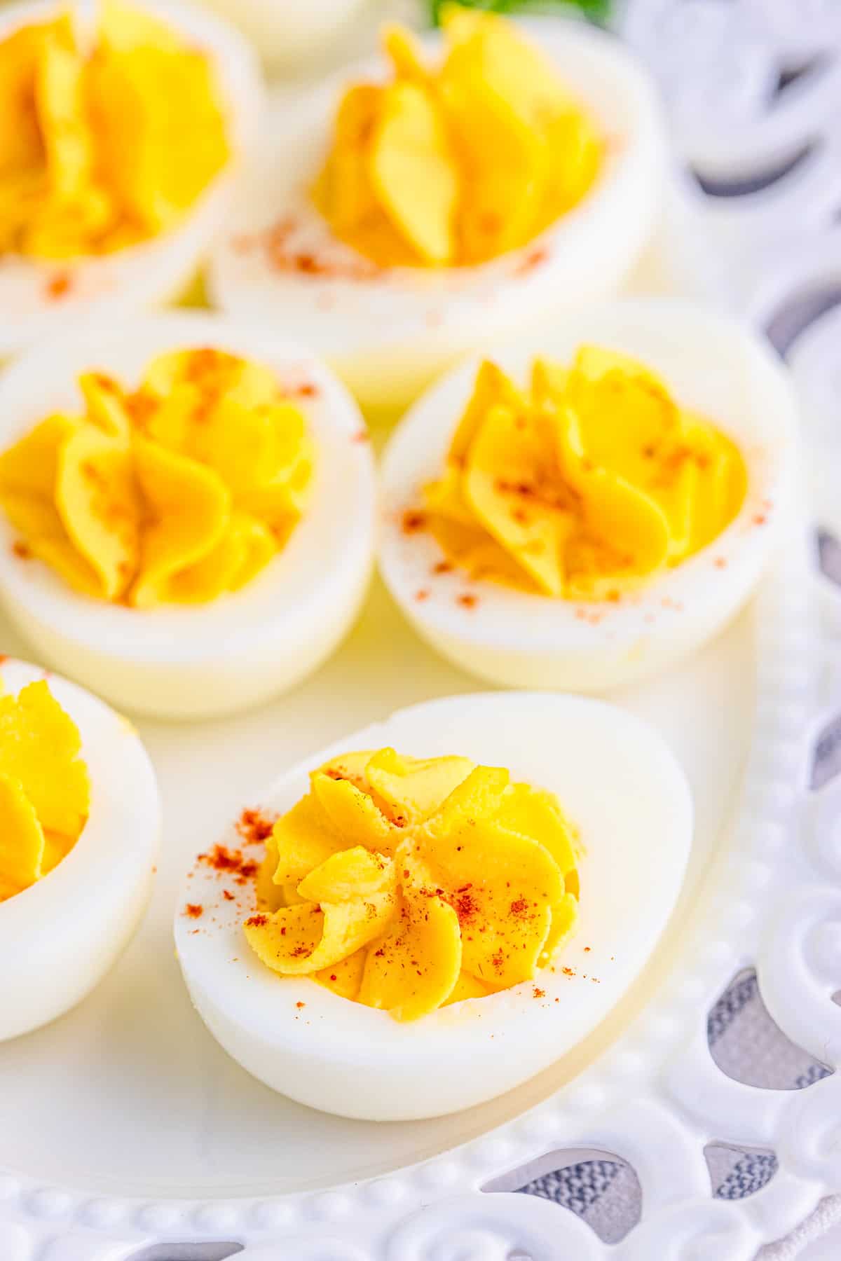 Close up of Classic Deviled Eggs on white platter showing paprika garnish.