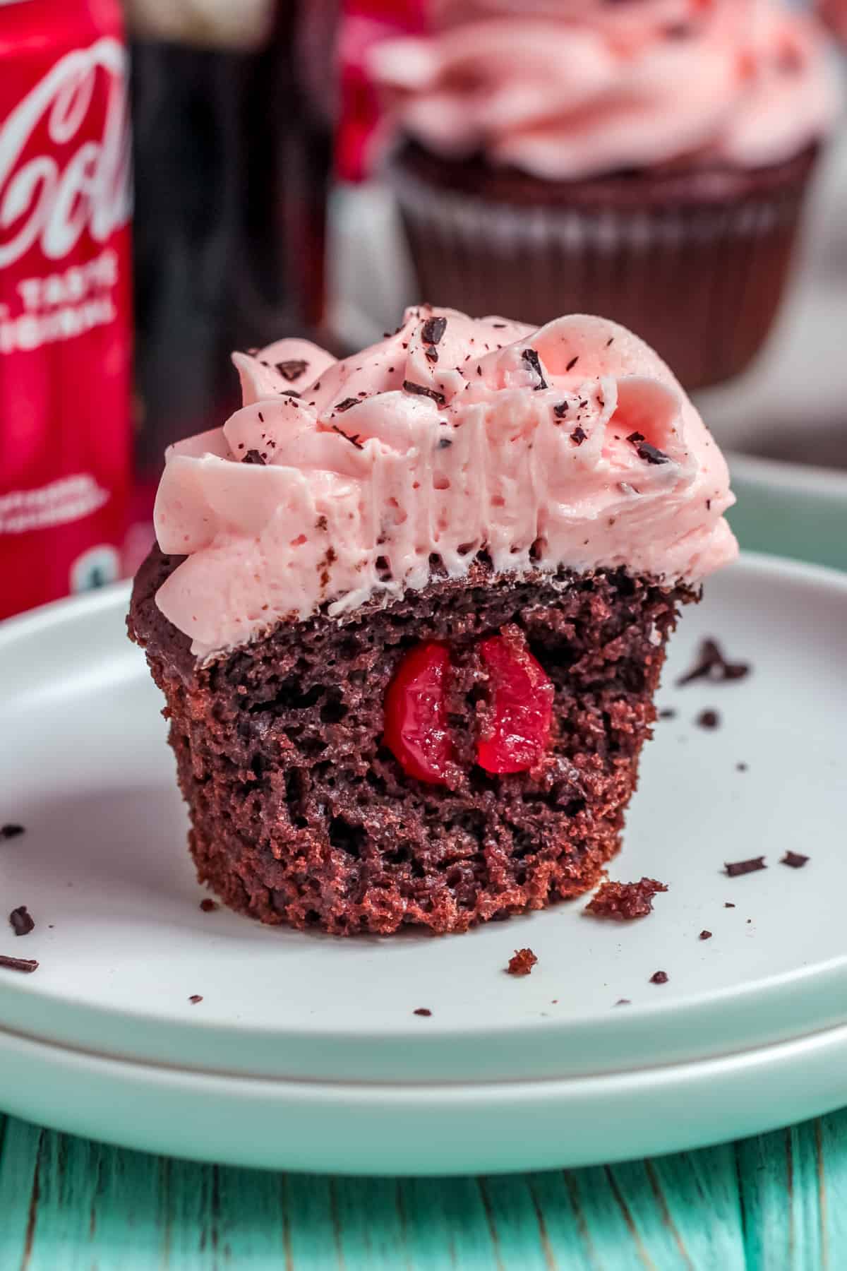 One of the Cherry Coke Cupcakes cut in half on plate showing cherry in center.