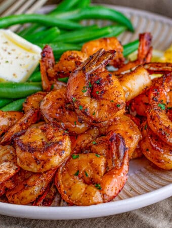 Square image of shrimp on plate with green beans.
