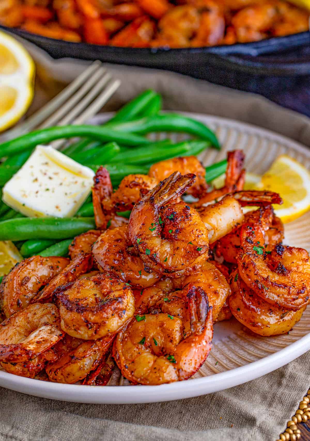Blackened Shrimp on white plate served with some green beans on the side.