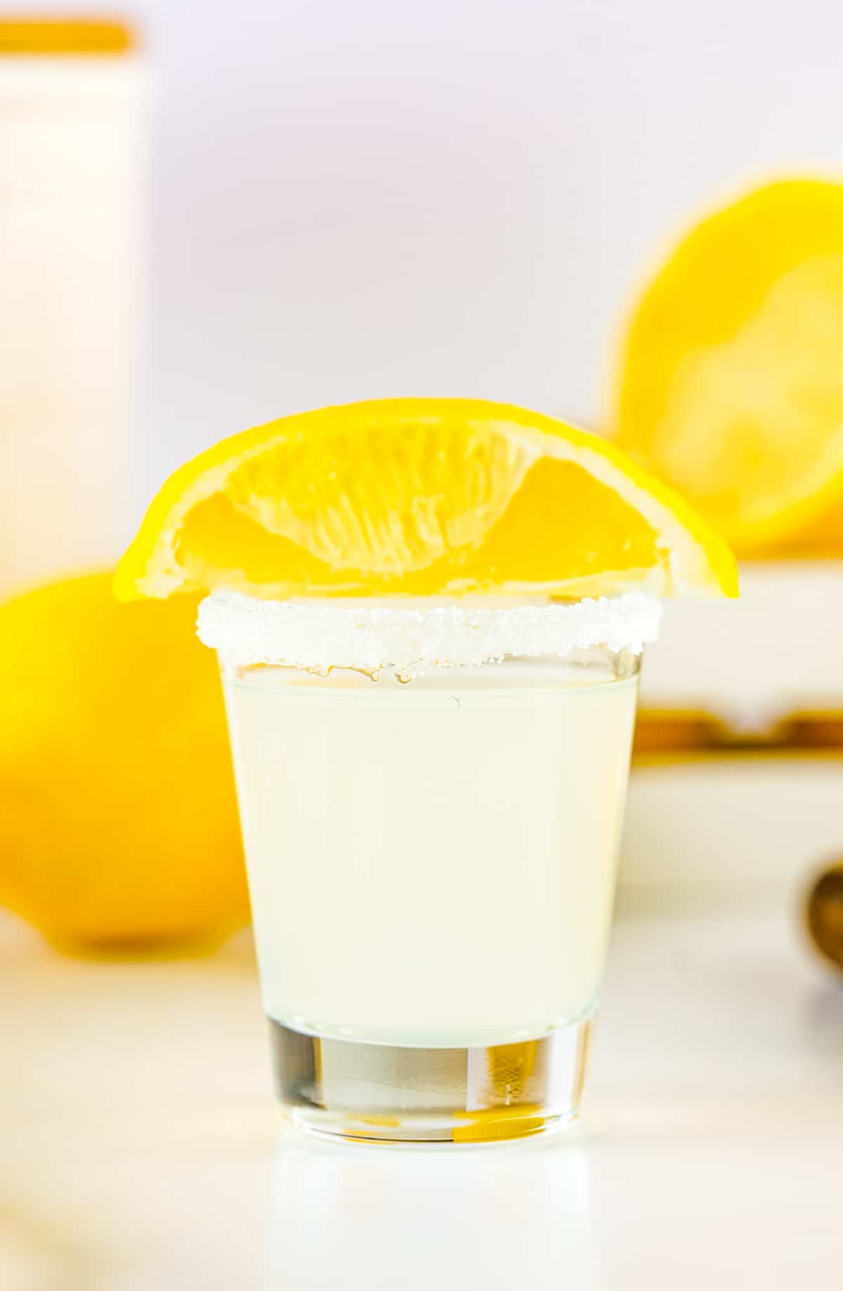 One Lemon Drop Shot with shot glass rimmed with sugar and topped with a lemon wedge.