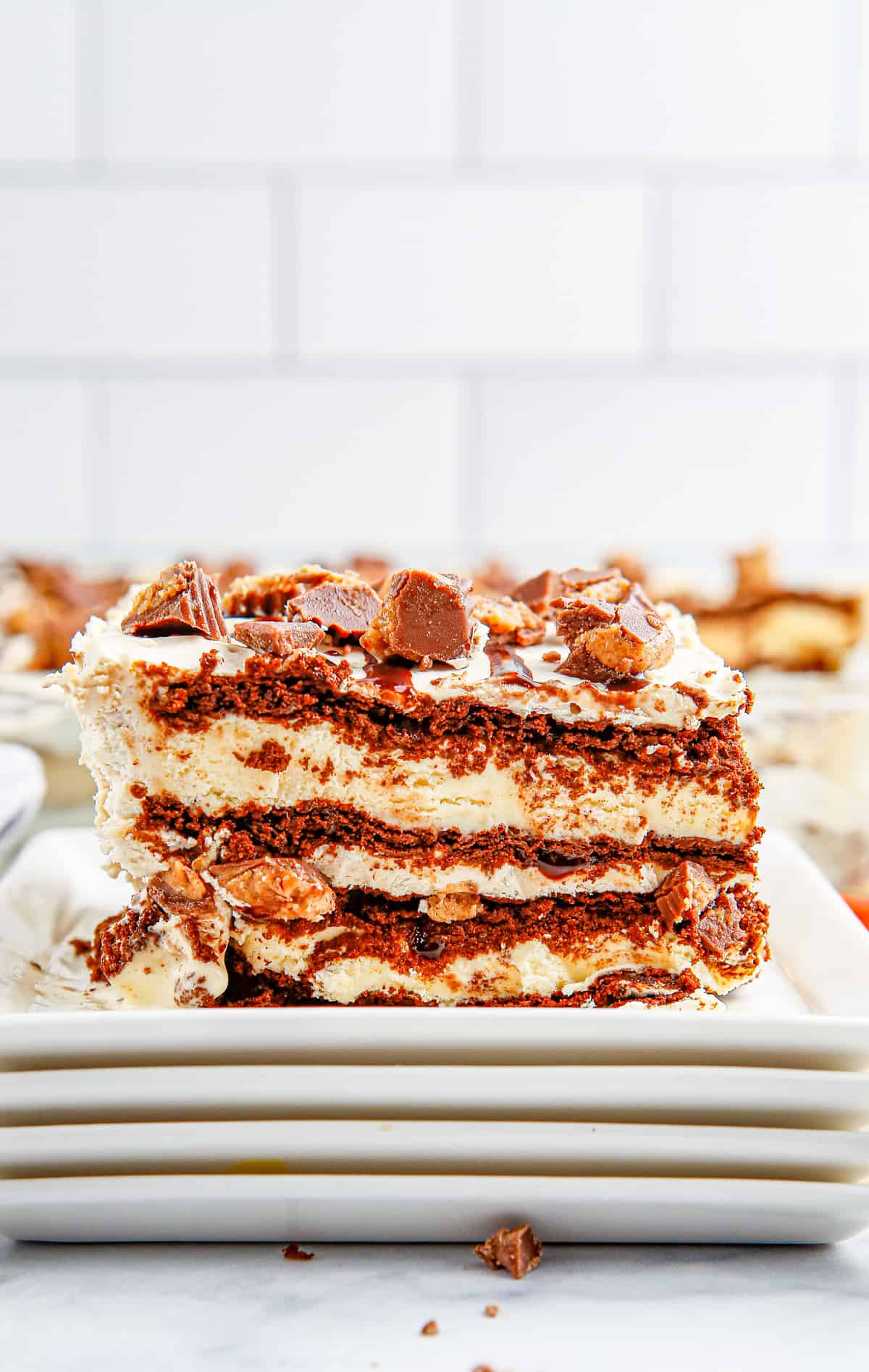 One slice of the Reese's Ice Cream Cake on stacked square white plates.