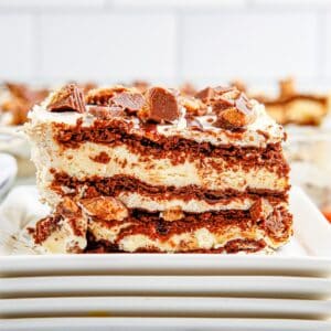 Close up square image of a slice of cake on a stack of square white plates.