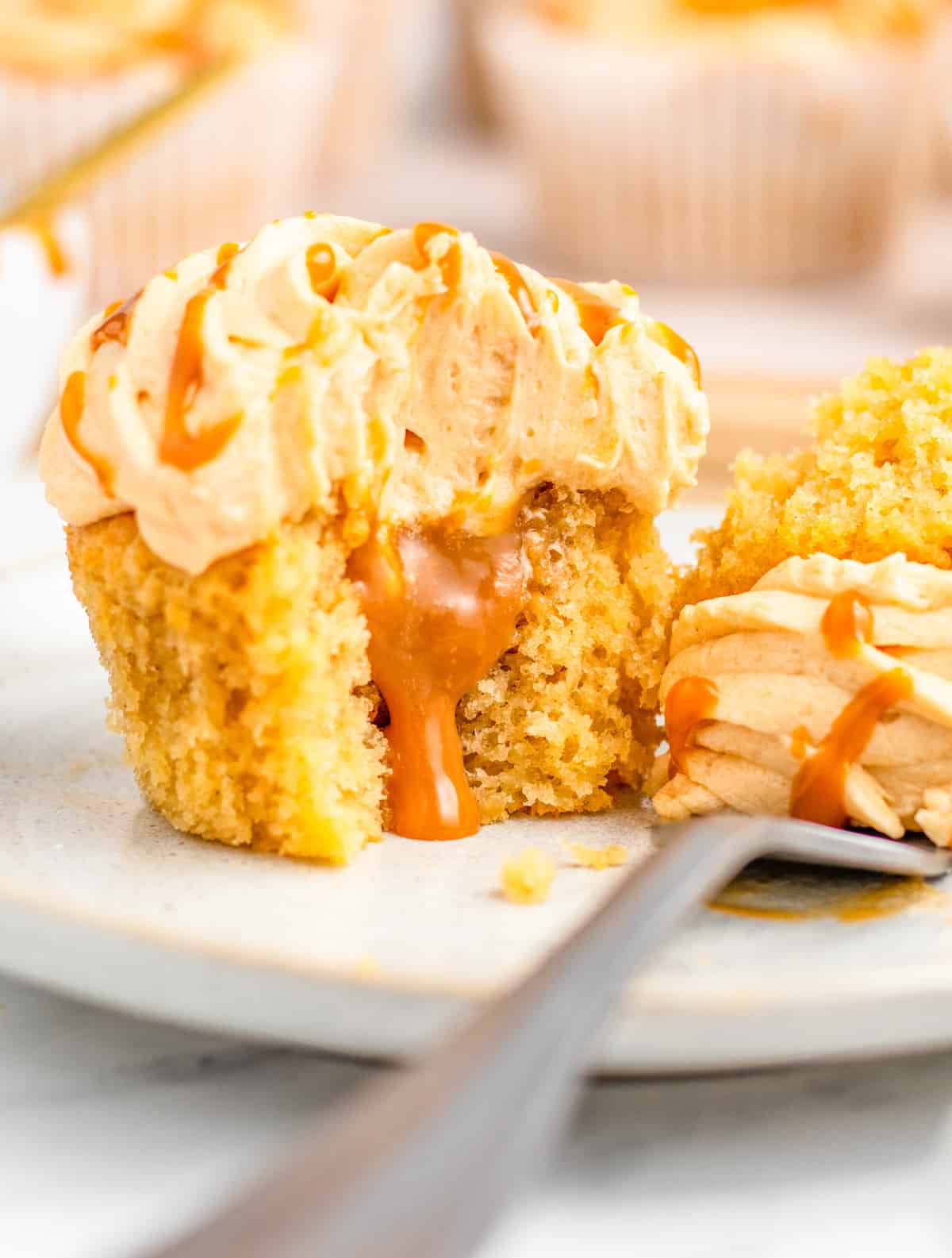 One Salted Caramel Cupcake on plate with a bite cut out showing the salted caramel center.