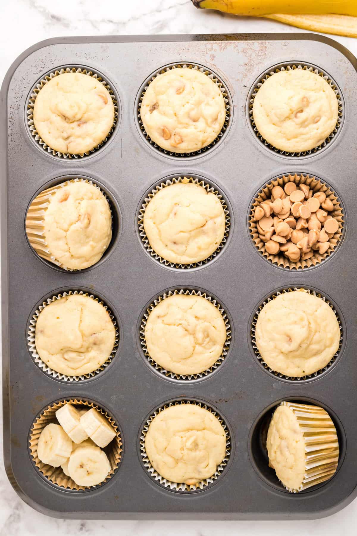 Finished Pancake Muffins in baking tin with some wells filled up with bananas and peanut butter chips.