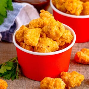 Close up square image of finished chicken pieces in a red cardboard container.