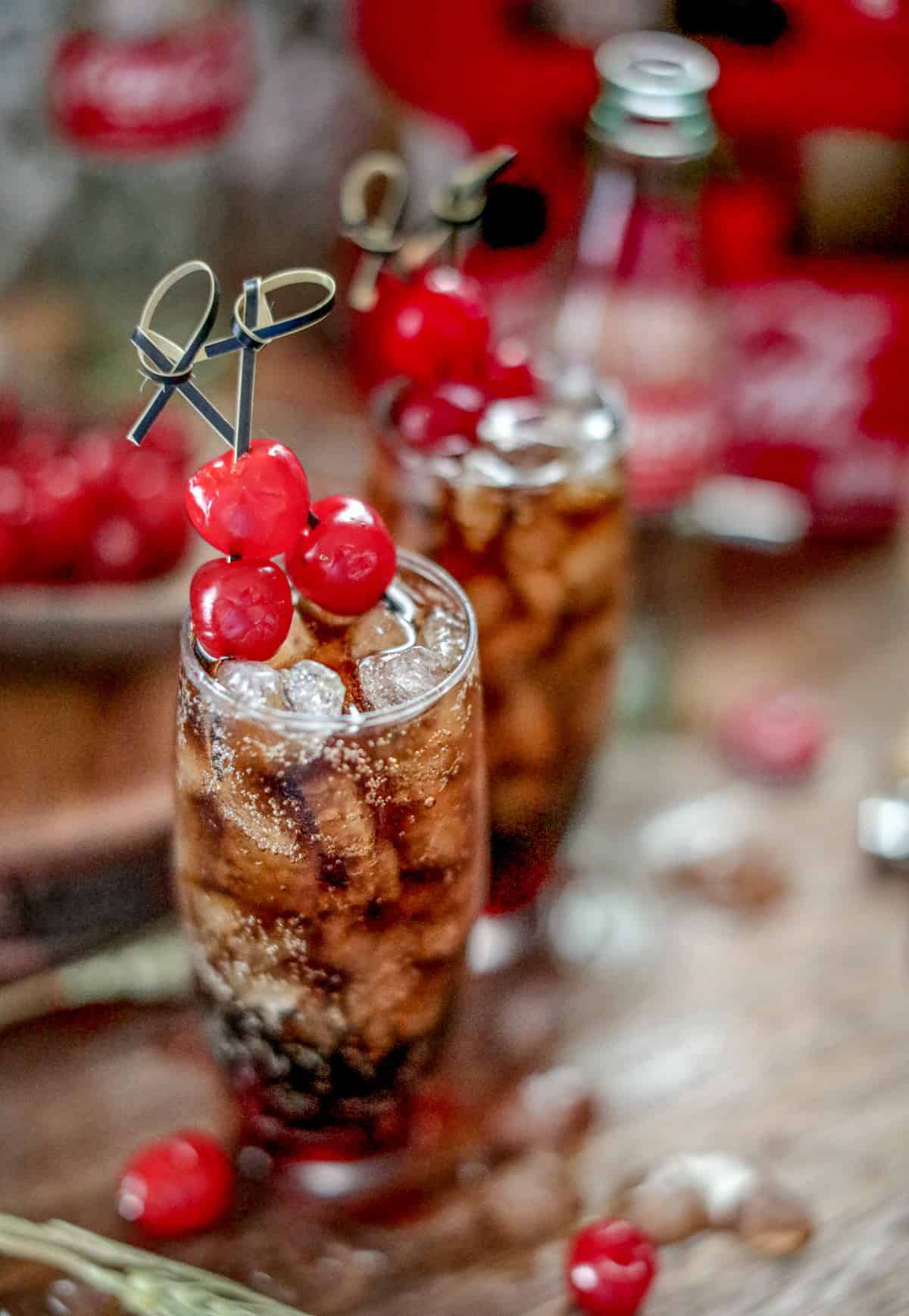 Roy Rogers Drink on wooden board with melted ice and cherries around it.