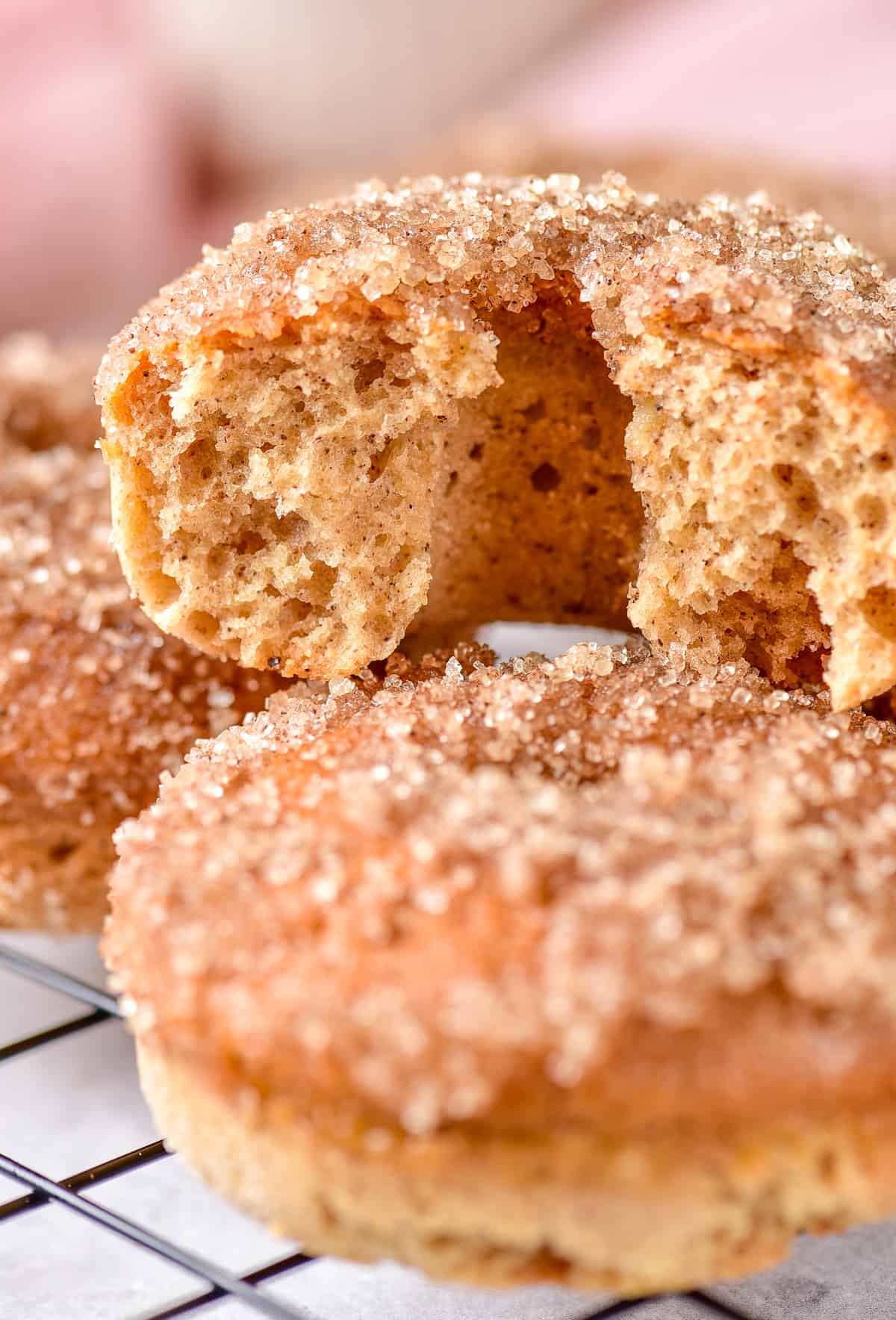Close up stacked donuts with cinnamon sugar topping with top one split in half showing the fluffy inside.