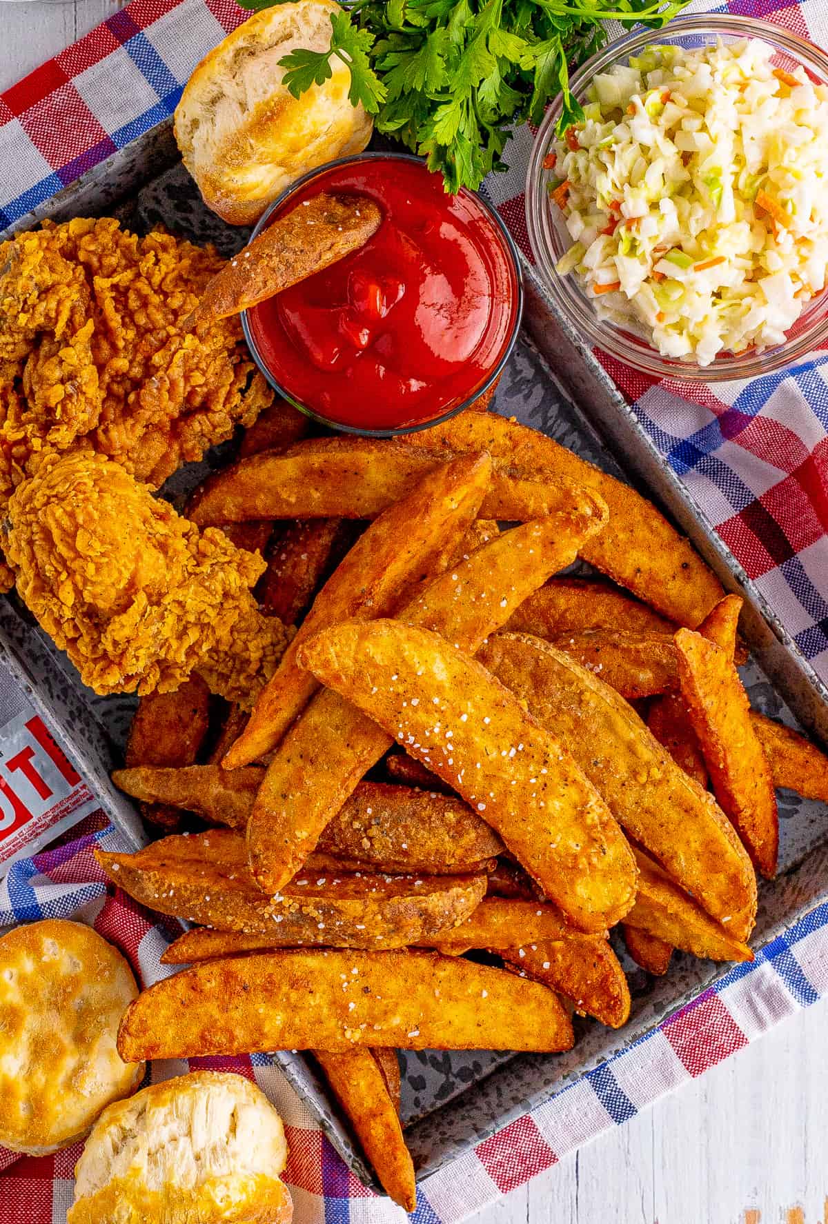 Overhead of Copycat KFC Potato Wedges in metal try with fried chicken, biscuits and coleslaw.