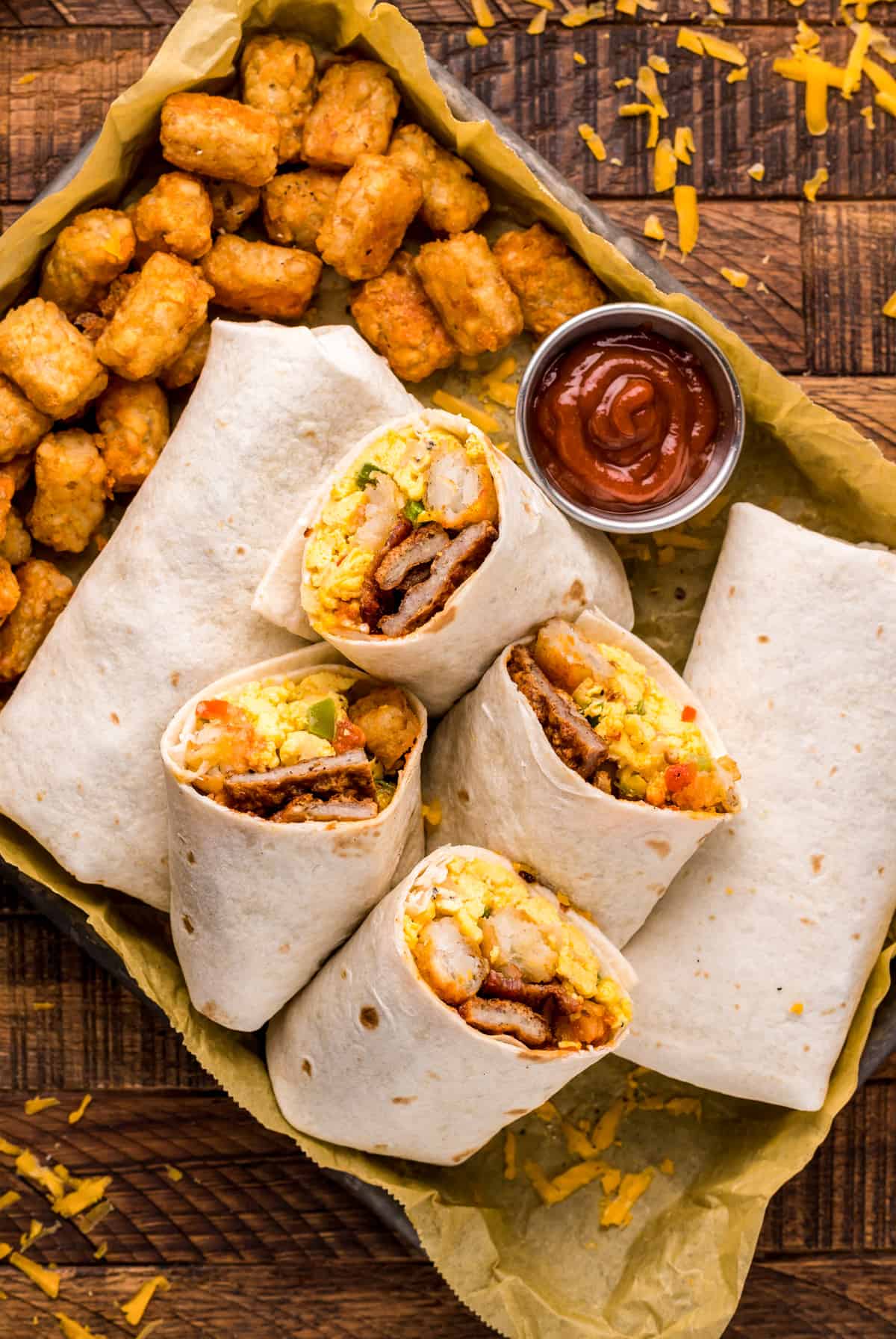 Overhead of burritos on pan cut in half and stacked with picante sauce and tater tots.