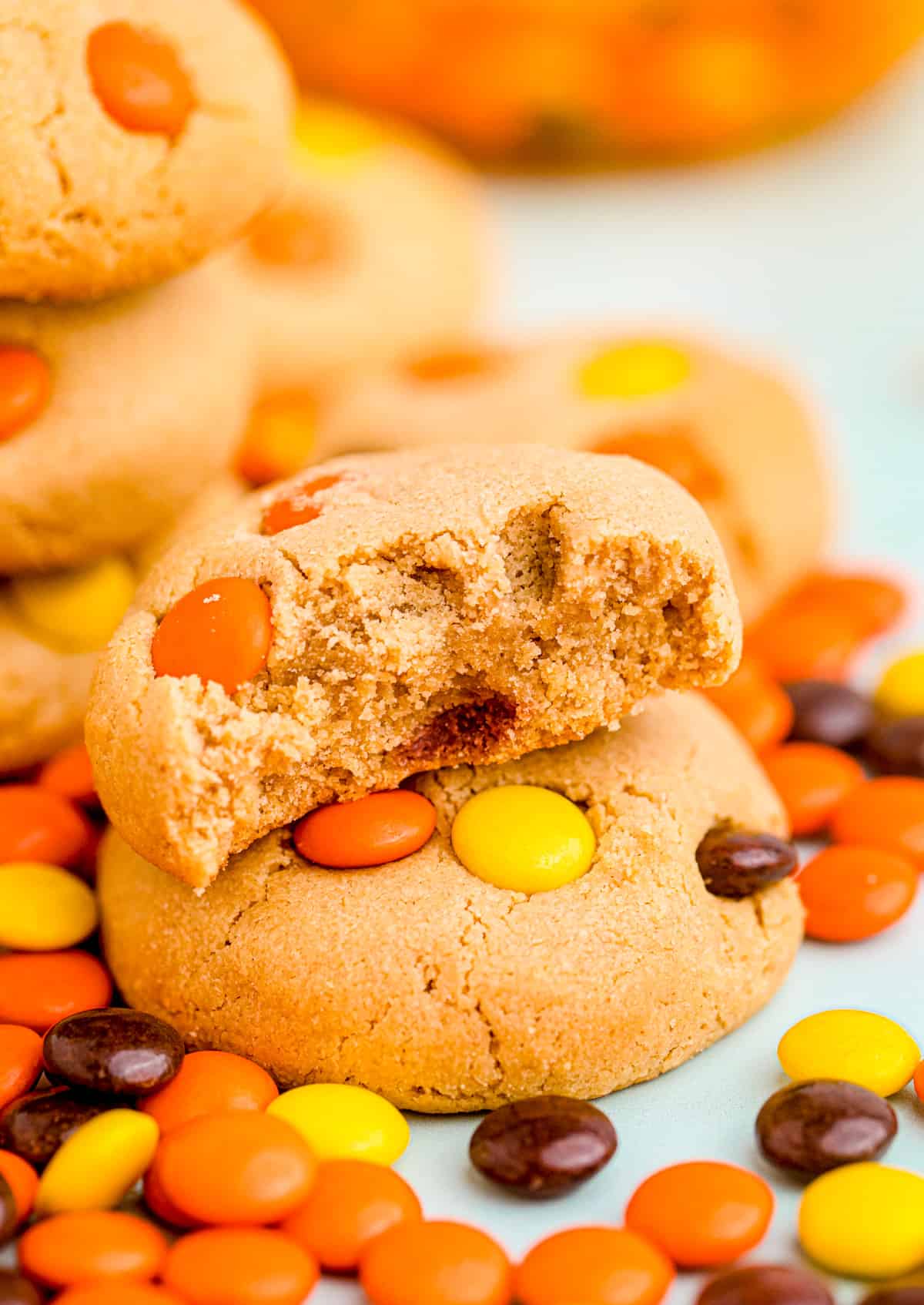 Two stacked cookies with one cookies with a bite taken out of it with Reese's Pieces around cookies.