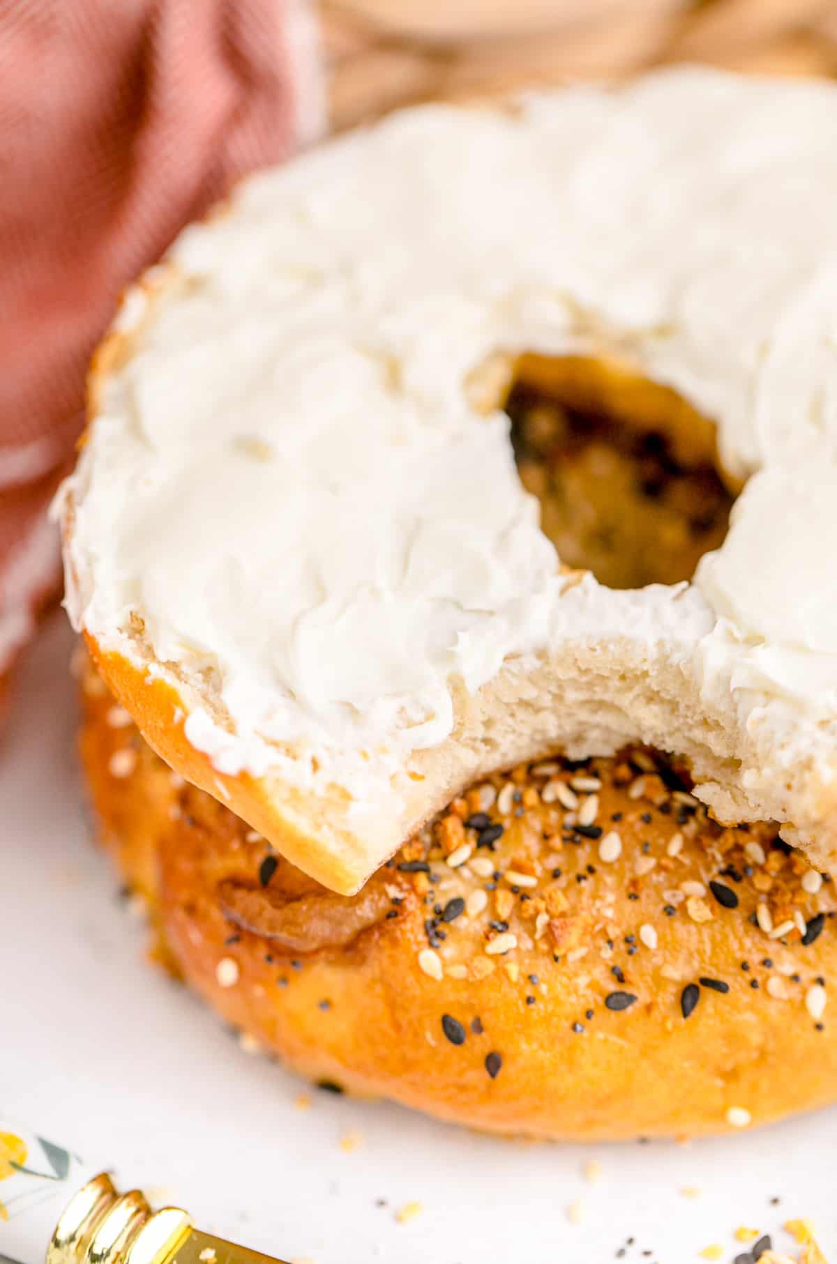 Sliced bagel topped with cream cheese and a bite taken out of it.