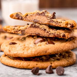 Close up square image of stacked cookies with top cookies cut in half showing the Reese's inside.