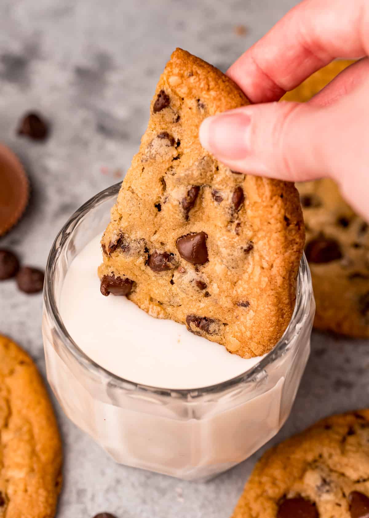 Hand dipping a half of a cookie in milk.