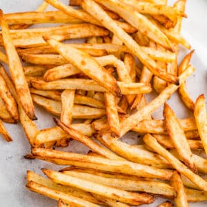Close up square image of Fries on parchment paper.