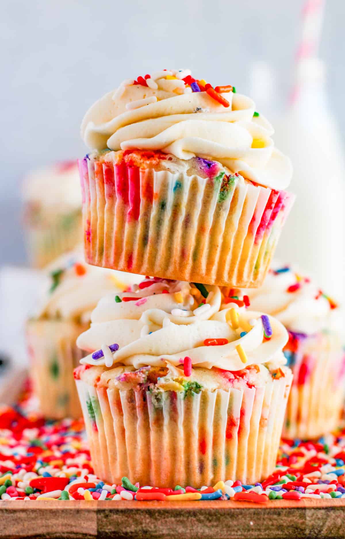Two stacked Funfetti Cupcakes on wooden board.