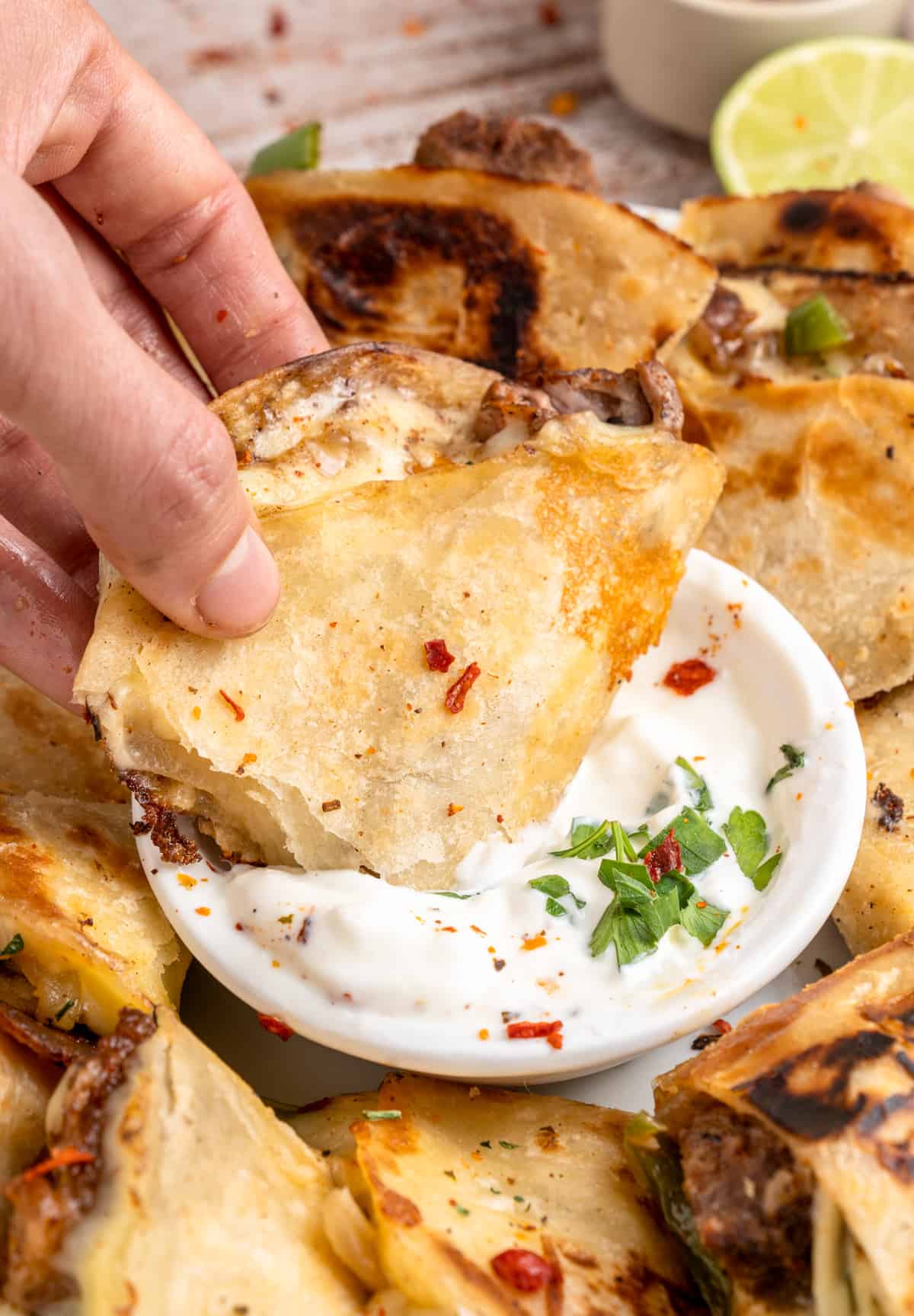 Hand dipping one of the quesadilla triangles into the sour cream.