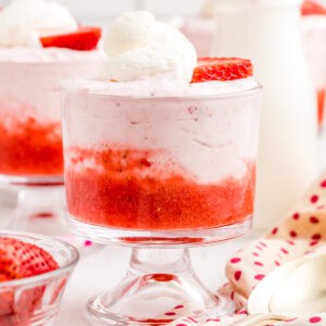 Close up of mousse in serving dish layered with strawberry puree, mousse, whipped topping and sliced strawberry.