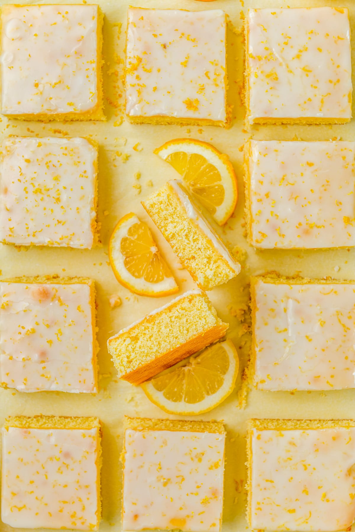 Overhead of Lemon Brownies cut on parchment paper with two on their side with lemon slices.